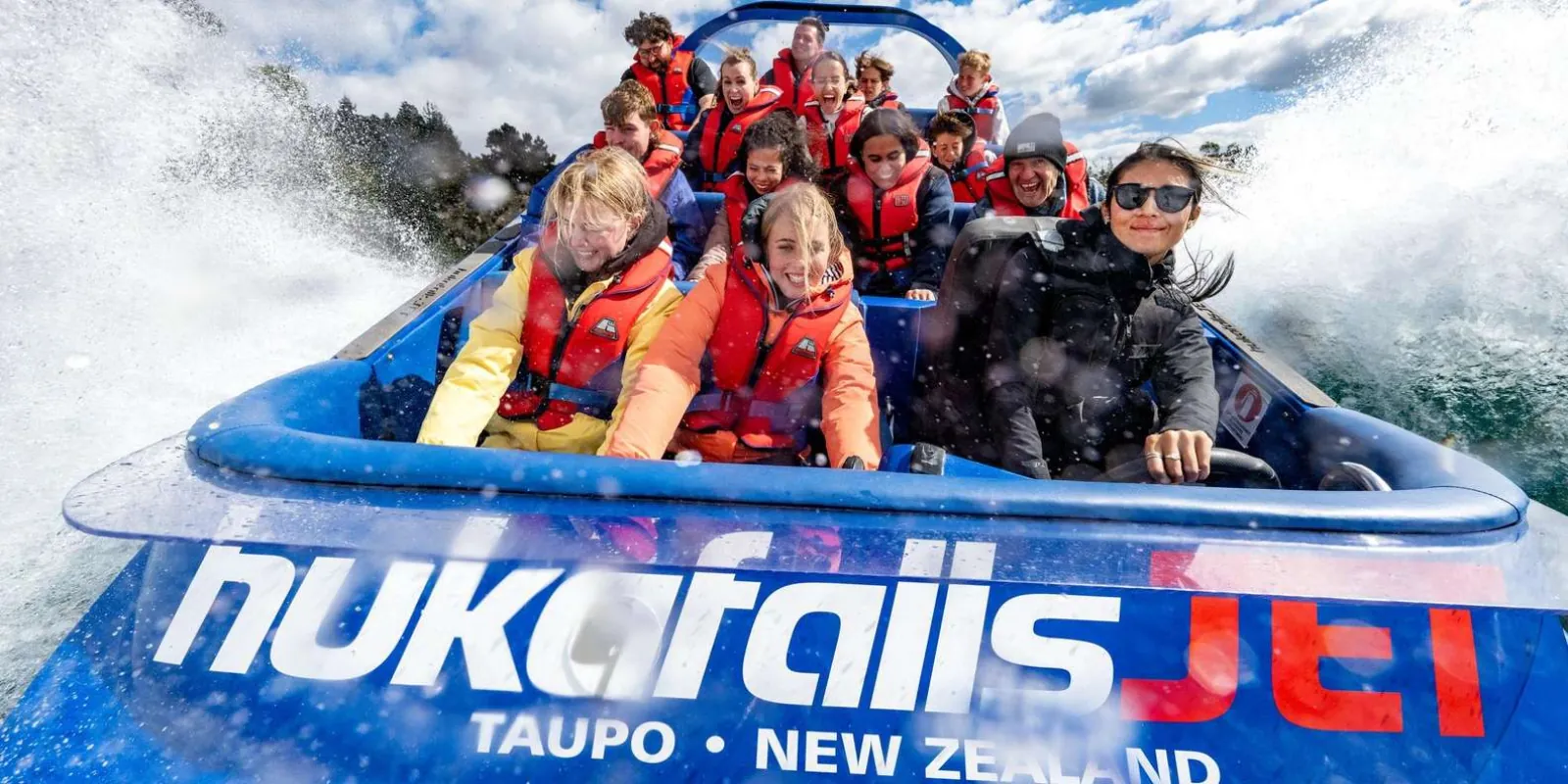 Passengers in life jackets aboard a blue Hukafalls Jet boat