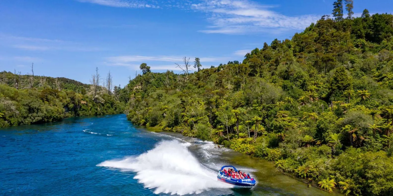 Blue jet boat making a turn on the turquoise Waikato River