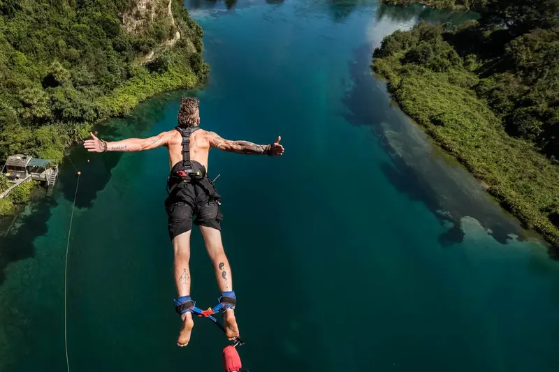 Bungy jumper diving towards the Waikato River with arms outstretched